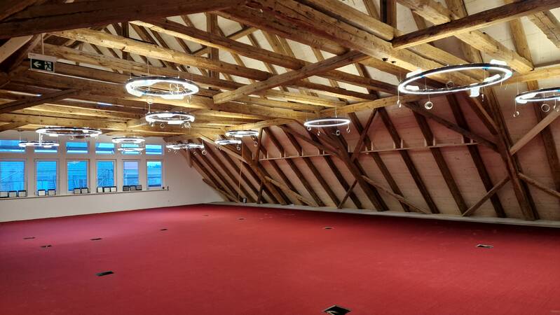 Großer Bürgersaal mit viel Holz im Gebelk und rotem Teppich